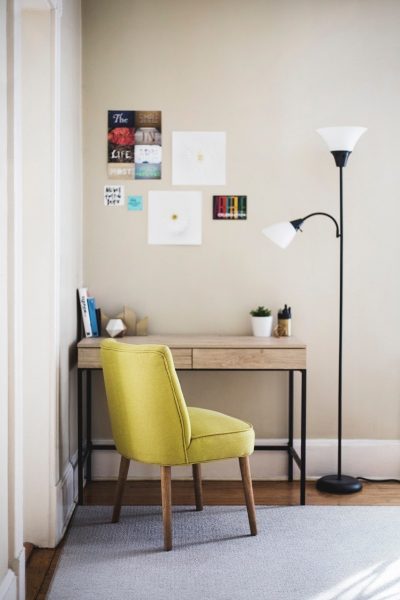 Dónde poner tu oficina en casa: mesita de escritorio pequeña en esquinita de una casa, con una silla verde, un flexo y unos cuadros pequeños.