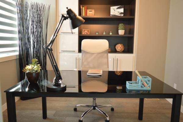 Despacho correctamente iluminado para trabajar en casa. Iluminación correcta en tu oficina en casa. Silla y mesa de escritorio con flexo, ventana en el lateral izquierdo y librería al fondo.