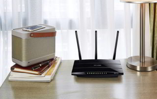 Cómo mejorar la cobertura WIFI de casa con este router WIFI TPLink Archer. Router sobre escritorio junto a libros y móvil sobre un altavoz Bluetooth.
