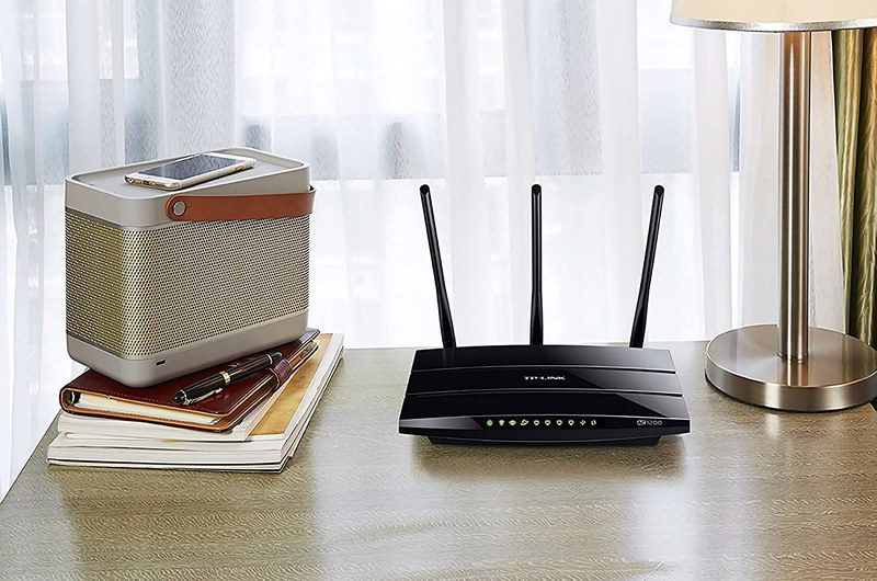 Cómo mejorar la cobertura WIFI de casa con este router WIFI TPLink Archer. Router sobre escritorio junto a libros y móvil sobre un altavoz Bluetooth.