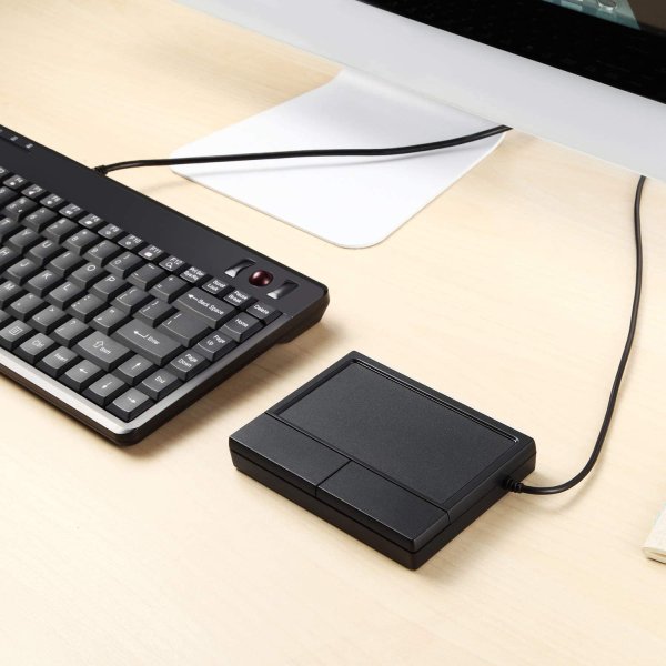 Touchpad externo como sustituto del ratón para escritorios pequeños. Color negro junto a teclado negro y pantalla blanca.